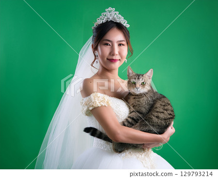 可愛的微笑女孩和穿著婚紗的貓看著相機 129793214