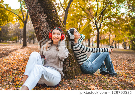 Woman Sitting Next to Tree Wearing Headphones 129793585