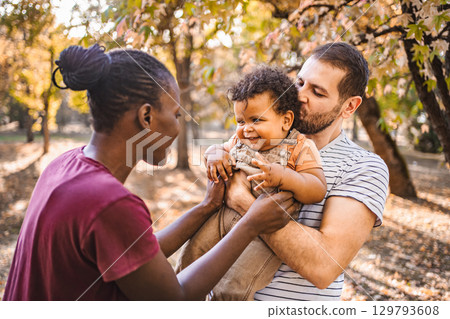 Boy in the arms of his parents in the park Boy in the arms of his parents in the park 129793608