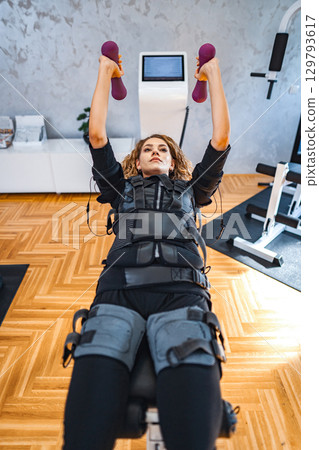 Empowered strength training session with muscle stimulation 129793617