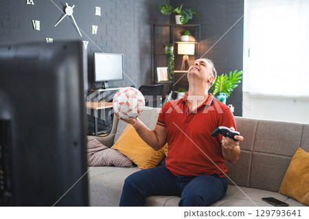 Middle age Caucasian man playing soccer video game at home 129793641