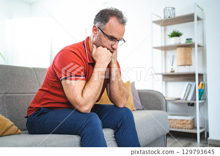 Man sitting alone at home looking sad and distraught 129793645