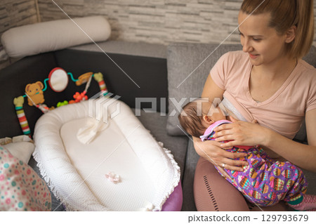 Breastfeeding mother lovingly cares for her infant in cozy living room 129793679