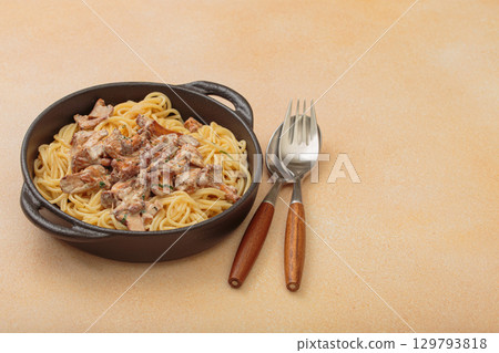 Creamy chanterelle mushroom pasta in cast iron pan with fork and spoon, space for text Creamy chanterelle mushroom pasta in cast iron pan with fork and spoon, space for text 129793818