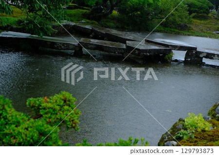 A stone bridge and pond in a Japanese garden, glistening with rain (Kenrokuen Garden, Kanazawa - a tranquil and serene atmosphere) A stone bridge and pond in a Japanese garden, glistening with rain (Kenrokuen Garden, Kanazawa - a tranquil and serene atmosphere) 129793873