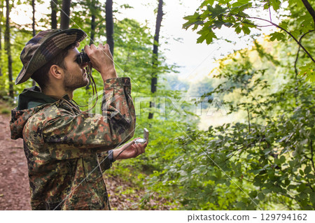 Soldier exploring forest using binoculars and compass 129794162