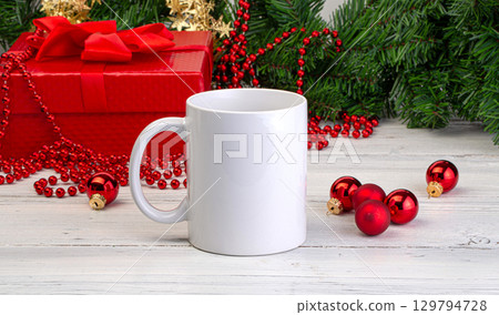 White mug standing on white wooden table with christmas decorations and red gift box White mug standing on white wooden table with christmas decorations and red gift box 129794728