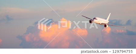Jet plane flying high above dramatic cloudscape during golden hour 129794755