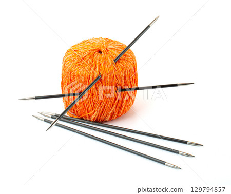 Orange yarn ball with knitting needles on white background 129794857