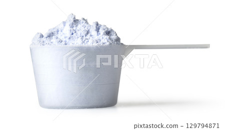 Measuring scoop overflowing with laundry detergent powder on white background Measuring scoop overflowing with laundry detergent powder on white background 129794871