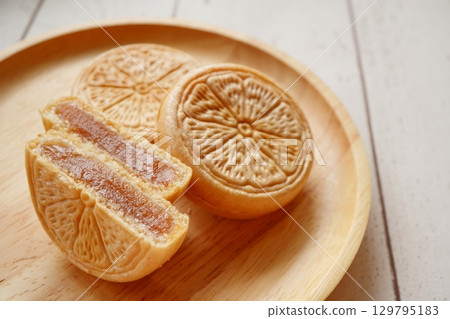 Cross section of a mandarin orange-patterned mochi served on a wooden plate 129795183