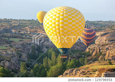 Colorful hot air balloons flying over stunning landscapes in Turkey during sunrise Colorful hot air balloons flying over stunning landscapes in Turkey during sunrise 129796958