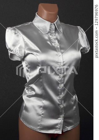 Elegant silver satin blouse with puff sleeves showcased on a mannequin Elegant silver satin blouse with puff sleeves showcased on a mannequin 129796976