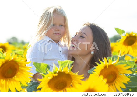 Joyful mother and child enjoying a sunny day in a sunflower field during summer 129796989