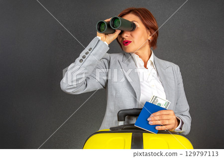 Woman with suitcase and binoculars looks for adventure with cash and passport in hand Woman with suitcase and binoculars looks for adventure with cash and passport in hand 129797113