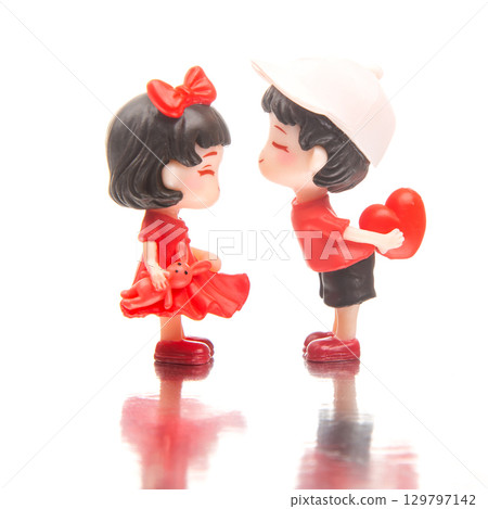 Miniature figures share a sweet moment, showcasing love and playfulness in a charming setup 129797142
