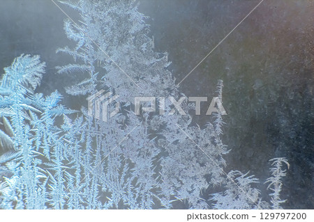 Frost patterns on glass create intricate designs at dawn in winter season 129797200