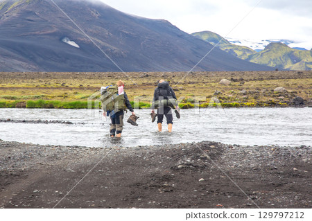 Adventurers crossing a river while hiking in the volcanic landscapes of Iceland Adventurers crossing a river while hiking in the volcanic landscapes of Iceland 129797212