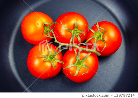 Fresh ripe tomatoes arranged on a dark plate ready for preparation or serving 129797214