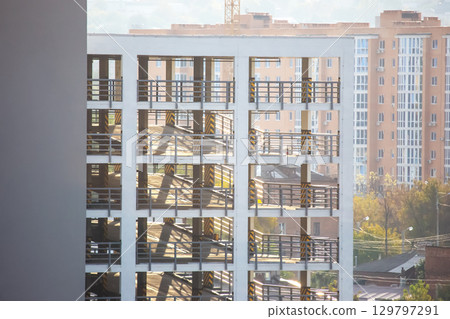 Modern urban construction with stacked floors and surrounding buildings during daylight hours 129797291