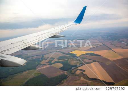 View of countryside landscape from airplane wing during afternoon flight over fields View of countryside landscape from airplane wing during afternoon flight over fields 129797292