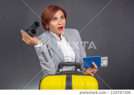 Surprised traveler with binoculars and suitcase preparing for adventure Surprised traveler with binoculars and suitcase preparing for adventure 129797306