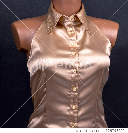 Elegant satin blouse displayed on mannequin against dark background Elegant satin blouse displayed on mannequin against dark background 129797321