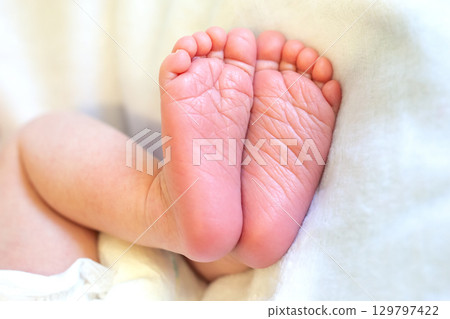 Baby feet resting peacefully against soft fabric in a cozy indoor setting during daylight hours 129797422