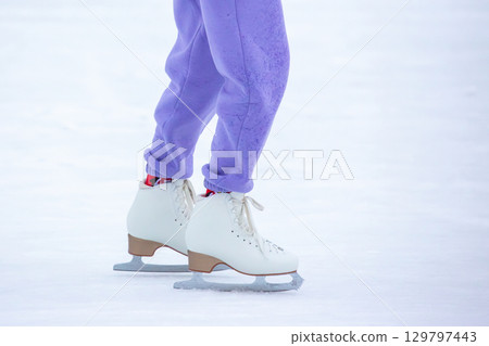 Young skater practices on a smooth ice rink during winter afternoon 129797443