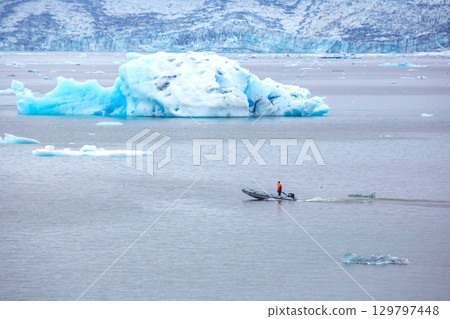 Exploring the icy waters of Iceland with a small boat near a giant glacier 129797448