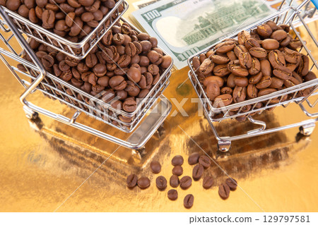 Coffee beans in miniature shopping carts with dollar bills on a golden surface Coffee beans in miniature shopping carts with dollar bills on a golden surface 129797581