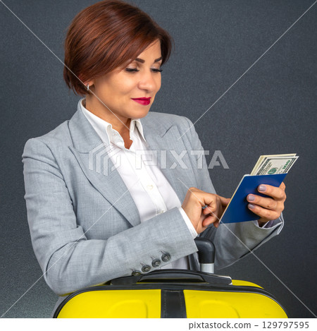 Business traveler prepares for departure with suitcase and travel documents in hand 129797595