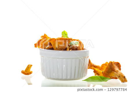 Yellow chanterelles and green basil in a bowl on white background Yellow chanterelles and green basil in a bowl on white background 129797784