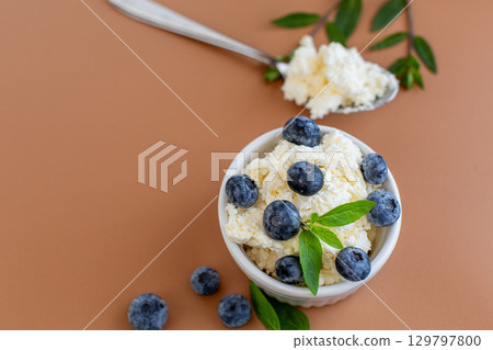 Seasonal composition cottage cheese blueberries and mint on a warm background Seasonal composition cottage cheese blueberries and mint on a warm background 129797800