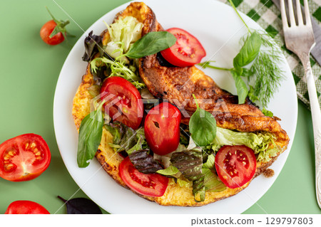 Low-calorie omelette with greens served isolated on green 129797803