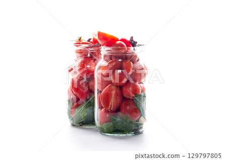 Ripe tomatoes and aromatic herbs in a glass jar close-up 129797805
