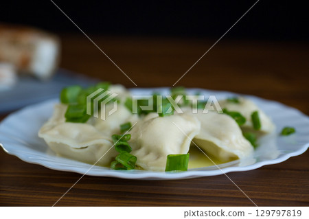 Hot dumplings in a plate with onions on a dark background 129797819