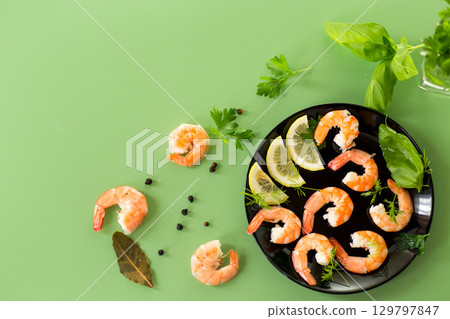 Appetizing boiled shrimps with lemon isolated on green background Appetizing boiled shrimps with lemon isolated on green background 129797847