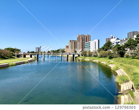 The clear blue autumn sky reflects on the surface of the Oto River and Tonobashi Bridge (Oto River Green Space, Okazaki City, Aichi Prefecture) 129798303