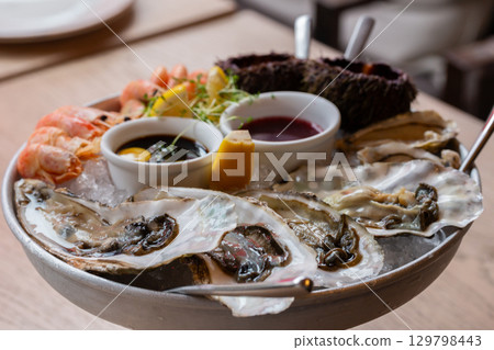 Seafood (oysters, shrimps, sea-urchins, mussels) are decoratively put on ice in a big plate 129798443