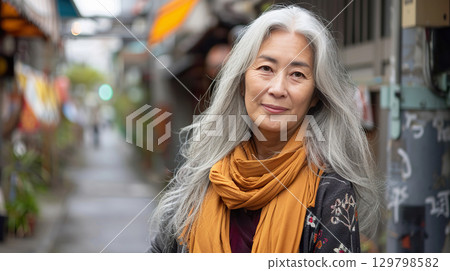 A mature Asian woman stands confidently on a bustling city street, reflecting autumn vibes A mature Asian woman stands confidently on a bustling city street, reflecting autumn vibes 129798582