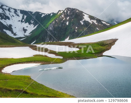 Glacial mountain lake with ice floes floating on it. 129798606