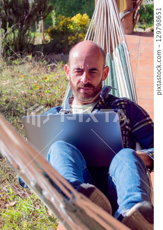 Man working on laptop in hammock 129798651