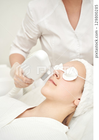Female caucasian adult receiving facial laser treatment in spa clinic 129800285