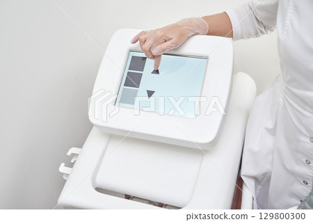 Female technician operating touchscreen control panel of modern medical Female technician operating touchscreen control panel of modern medical 129800300