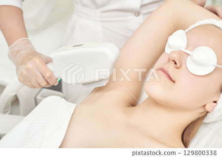 Young caucasian female receiving laser hair removal treatment in spa clinic Young caucasian female receiving laser hair removal treatment in spa clinic 129800338