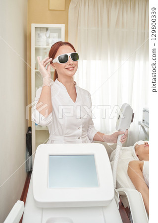 Female caucasian adult beautician preparing laser equipment for skin treatment Female caucasian adult beautician preparing laser equipment for skin treatment 129800339