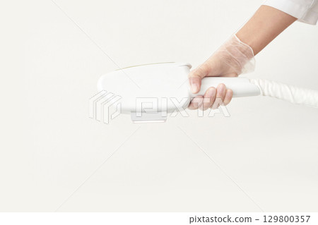 Hand holding modern ipl hair removal device against plain background Hand holding modern ipl hair removal device against plain background 129800357