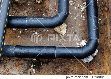New modern insulated urban pipeline installation construction site  exposed underground pipes in shored trenches. Insulated steel pipes lie connection engineering infrastructure upgrade work 129800466