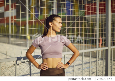 Portrait of a confident active sporty young woman standing in the park and looking to the side. 129800467